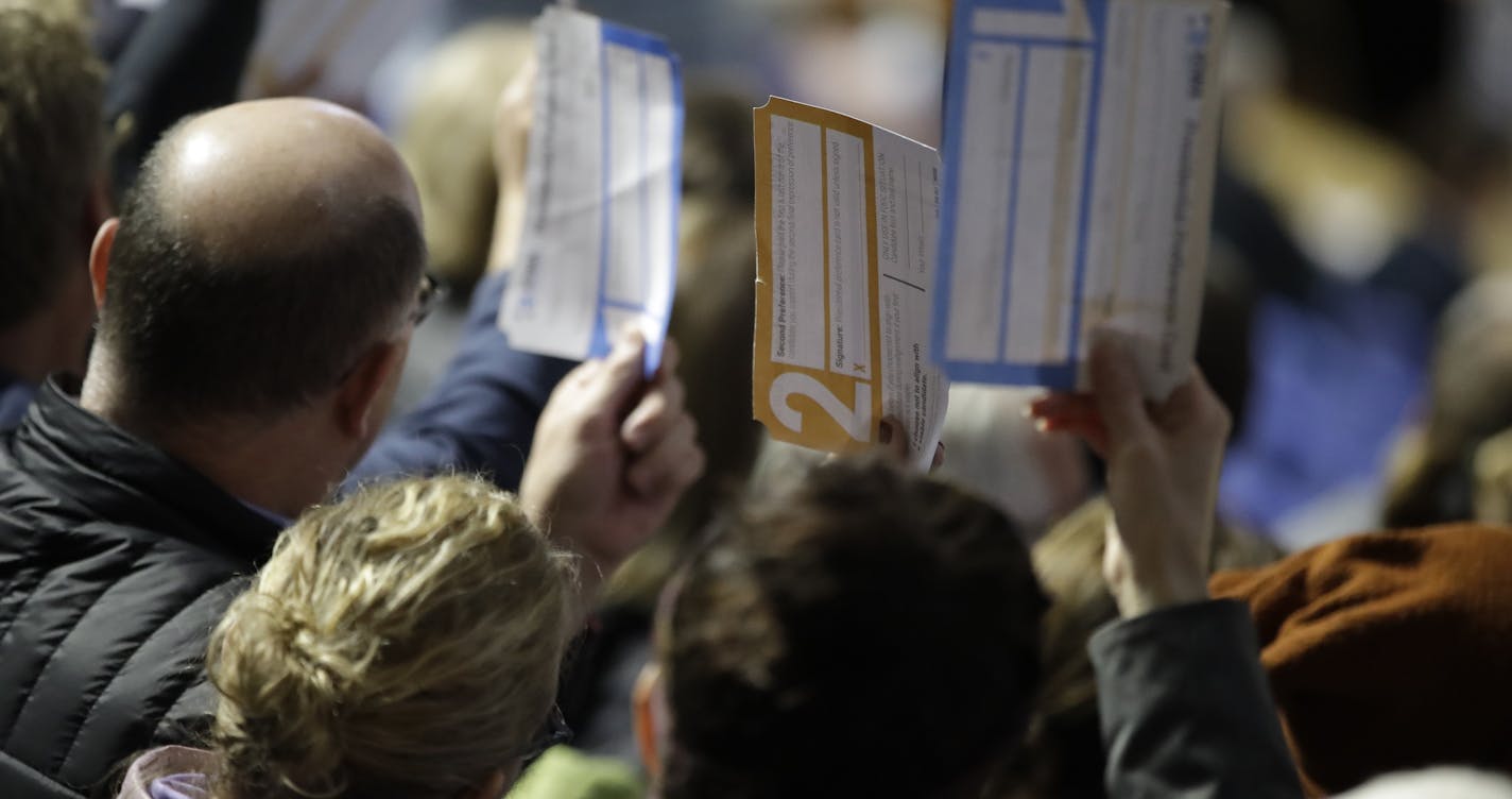 Precinct 68 Iowa Caucus voters seated in the Biden section hold up their first votes as they of the caucus as they are counted at the Knapp Center on the Drake University campus in Des Moines, Iowa, Monday, Feb. 3, 2020. (AP Photo/Gene J. Puskar)