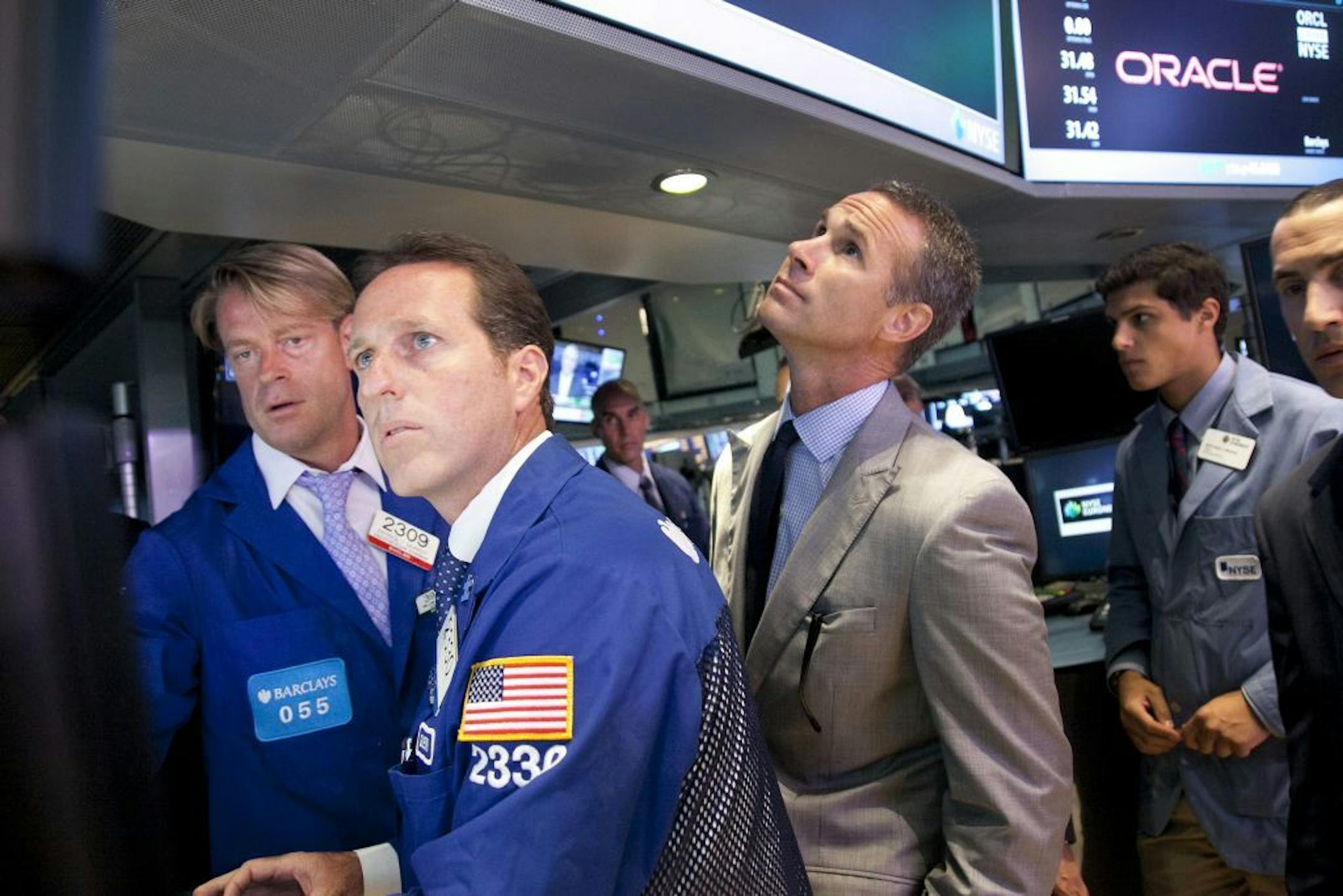 Glenn Carell, second from left, a senior floor official with Barclays Capital, monitors the stock price of Oracle as it opens for trading Monday, July 15, 2013 at the New York Stock Exchange. Oracle Corp., the multinational technology company based in Redwood City, Calif., transferred its listing from Nasdaq to the NYSE.