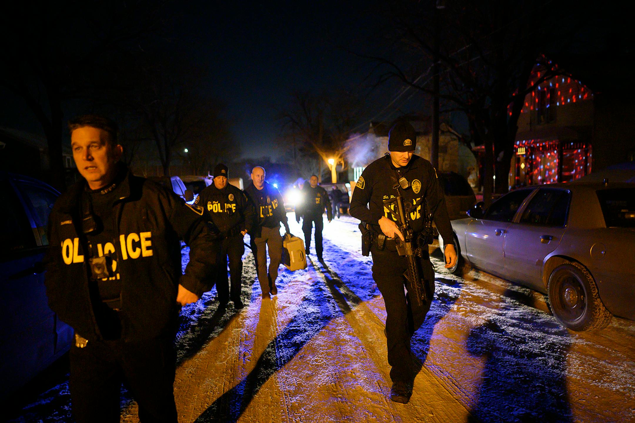 Members of the Saint Paul Police Department's gang unit, including Sgt. Shawn Campbell, left, and officer Colby Bragg, right, returned to their cars after executing a search warrant Wednesday night in the Central District which was related to a recent shooting.