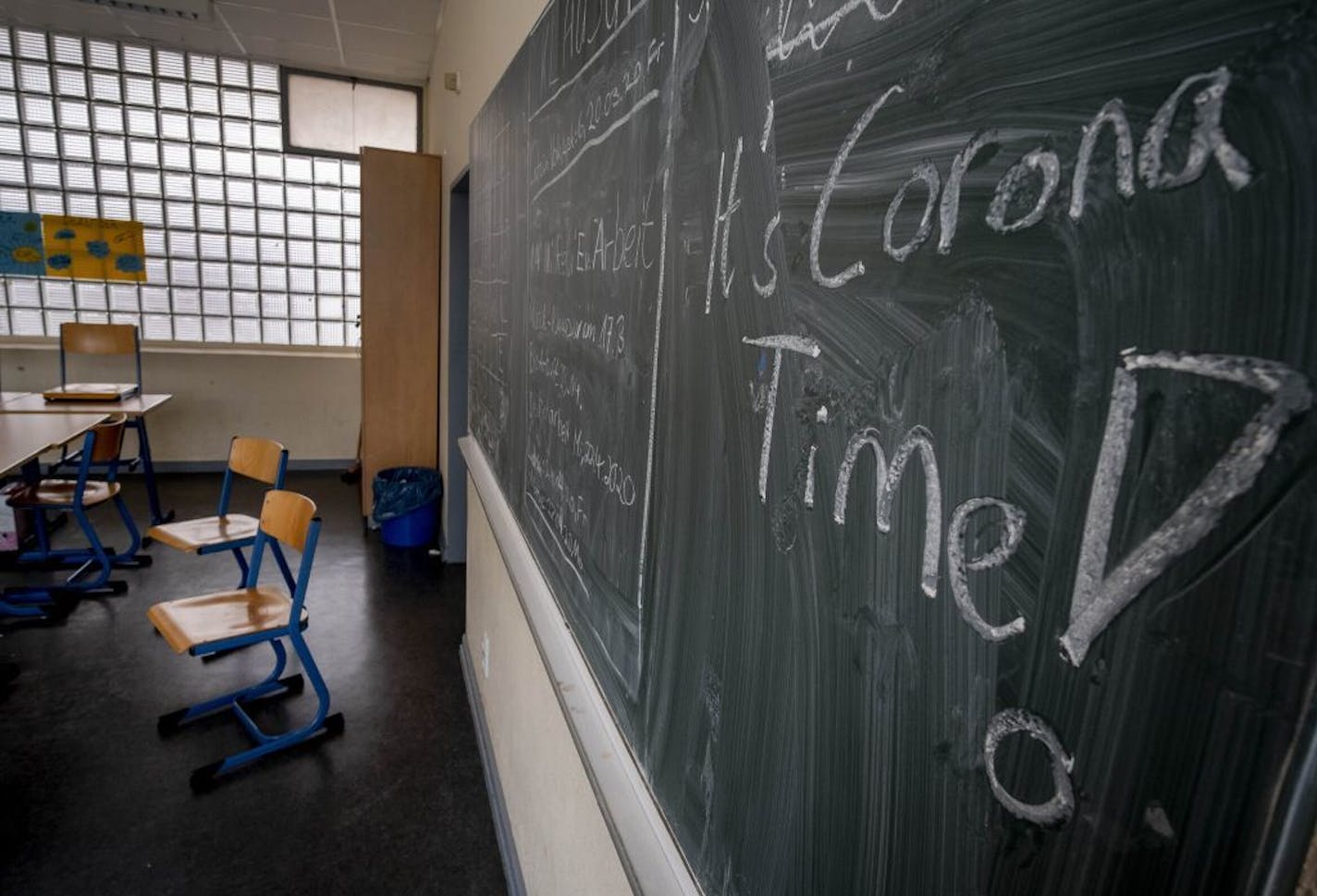 FILE -- In this Friday, March 13, 2020 photo a slogan on a chalkboard reads 'It's Corona Time' in an empty class room of a high school in Frankfurt, Germany, March 13, 2020. Germany plans to let smaller shops reopen next week after a weeks-long coronavirus shutdown and to start reopening schools in early May, but Europe's biggest economy is keeping strict social distancing rules in place for now.