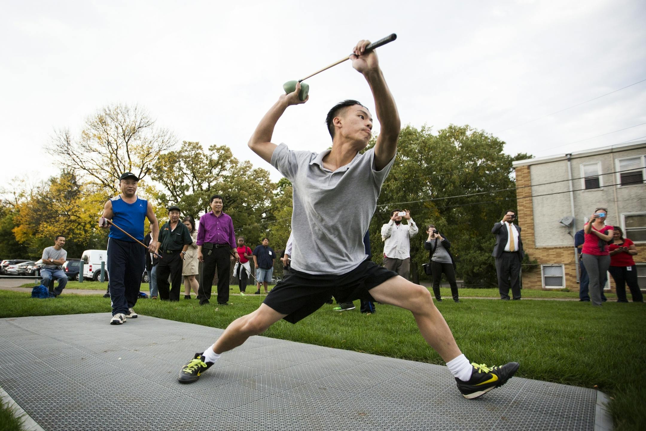 Keng Yang demonstrates the game of Tuj Lub for onlookers and media during the grand opening of the state's first Tuj Lub courts in St. Paul.