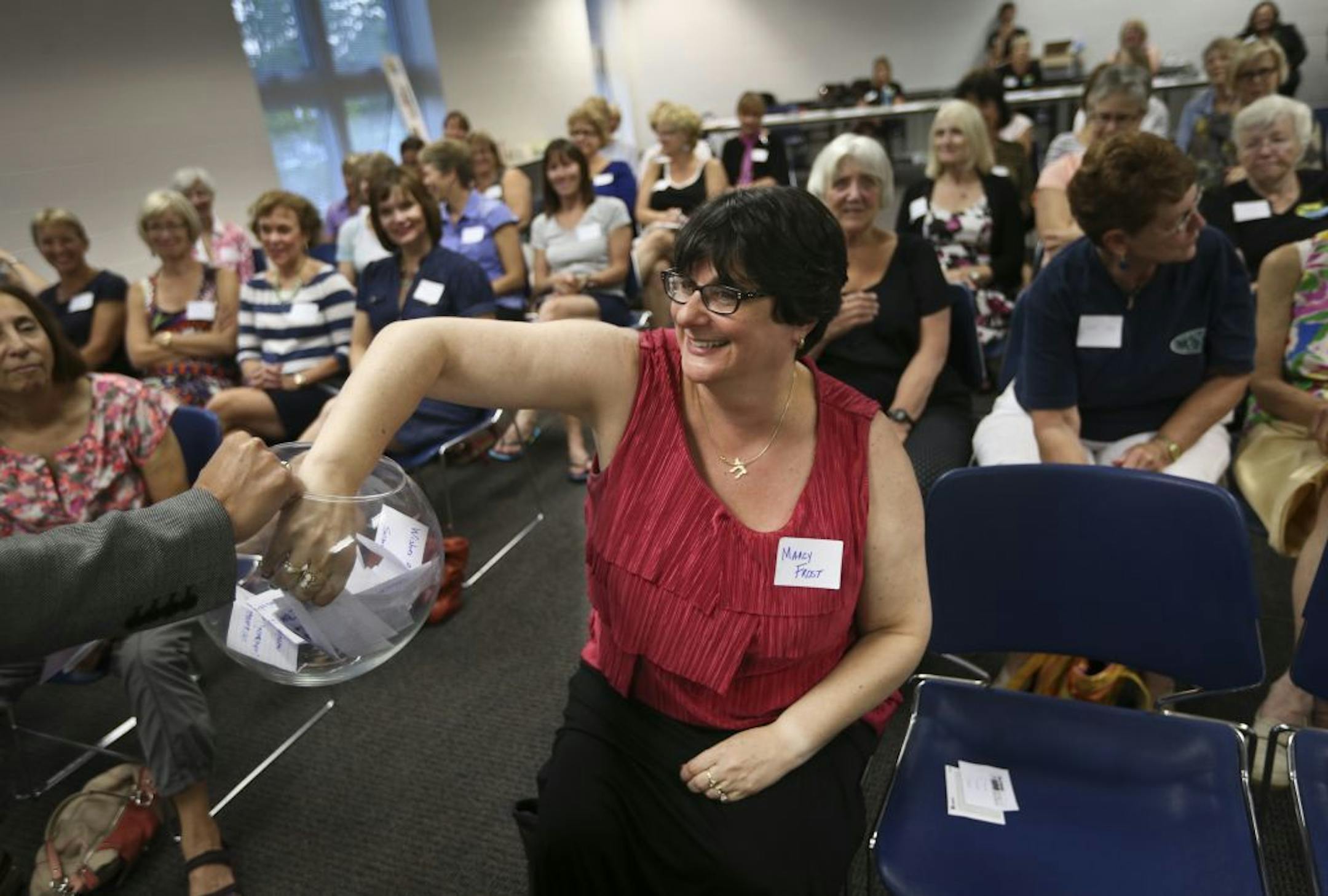 Marcy Frost had the honor of drawing one of three charities to be considered during a Power of 100 quarterly meeting where they choose a charity to donate to at the Community Center in Roseville, Minn., on Monday, September 9, 2013. The Power of 100 is a group of women who meet and choose a charity to collectively donate a $100 each to resulting in usually a $10,000 donation.