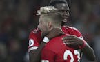 Manchester United's Luke Shaw, front, is hugged and congratulated by Manchester United's Paul Pogba, after he scored his sides second goal of the game