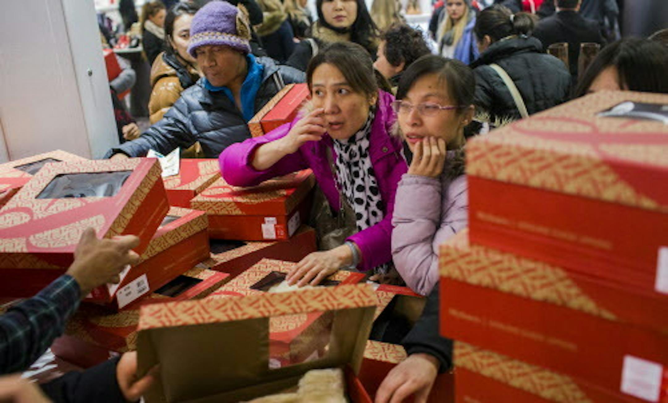 FILE -- Shoppers crowd around boots at Macy‚Äôs during the Black Friday sale event in New York, Nov. 28, 2013. Across the country, retailers are adding a projected 800,000 holiday workers to their ranks, their highest level of seasonal hiring since 1999, but forecasters warn that businesses could ultimately struggle to get households to spend more this holiday season. (Christopher Gregory/The New York Times)
