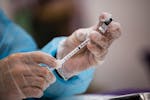 A health care worker prepares a dose of the Pfizer COVID vaccine at a clinic in San Juan, May 20, 2022.