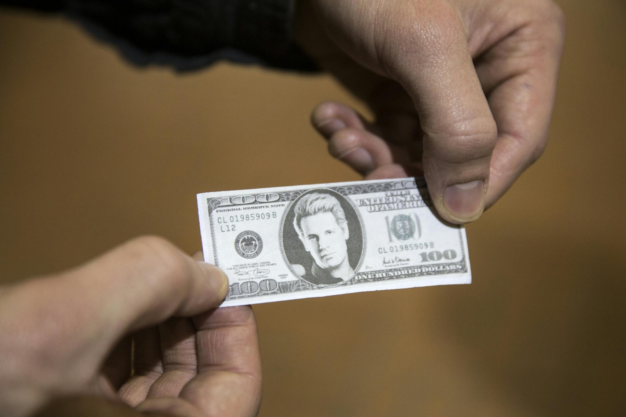 An attendee holds his ticket to a talk by Milo Yiannopoulos and Christina Hoff Sommers, which features a photo of Milo on the 100 dollar bill, at the Humphrey Institute of Public Affairs on the campus of the University of Minnesota in Minneapolis on Wednesday, February 17, 2016.