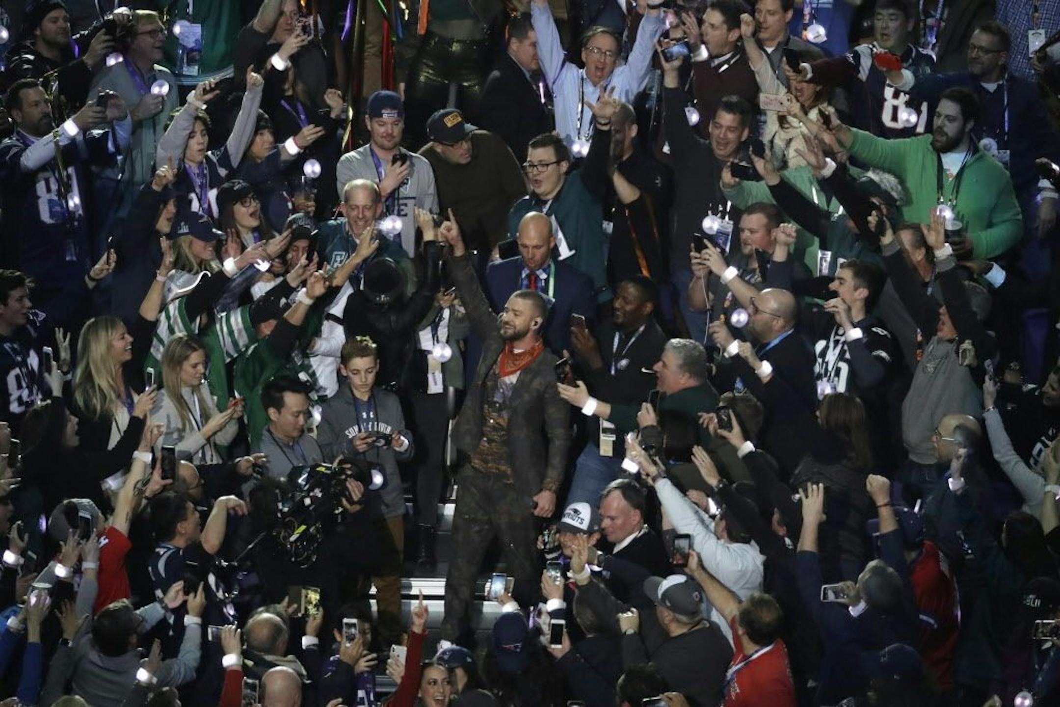 Ryan McKenna (in sweatshirt, standing to the left of Justin Timberlake) looks at his phone after taking a selfie with the Super Bowl halftime performer.