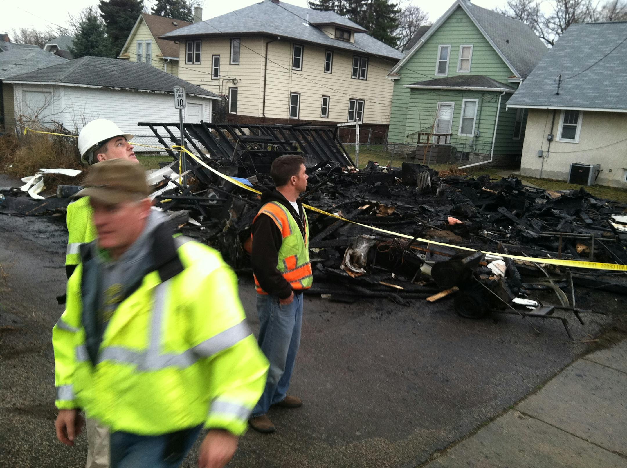 At the scene of a fatal garage fire in St. Paul, Comcast workers looked over the damage caused to a fiber cable line.