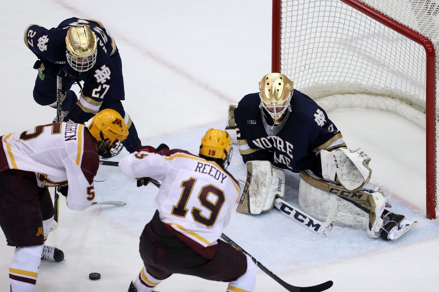 Notre Dame goaltender Cale Morris went down to make a save as Gophers defenseman Ryan Lindgren and forward Scott Reedy rushed the goal during a game last season.