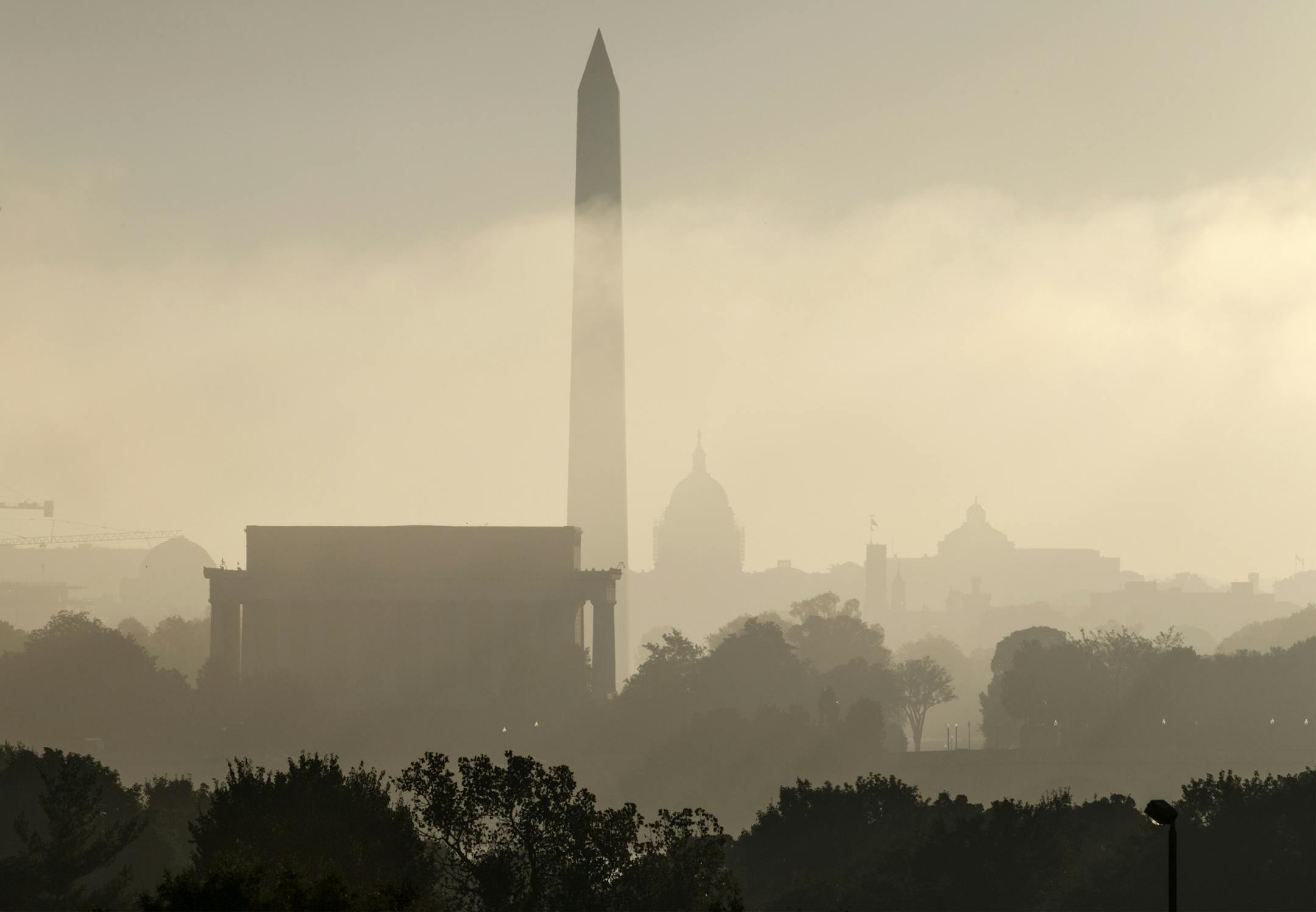 The monuments of Washington are silhouetted through the lifting fog over the nation's capitol as seen from an overlook in Arlington, Va., Friday, Sept. 26, 2014. From left are, the Lincoln Memorial, Washington Monument, the Capitol, the Smithsonian Castle, and the Library of Congress.
