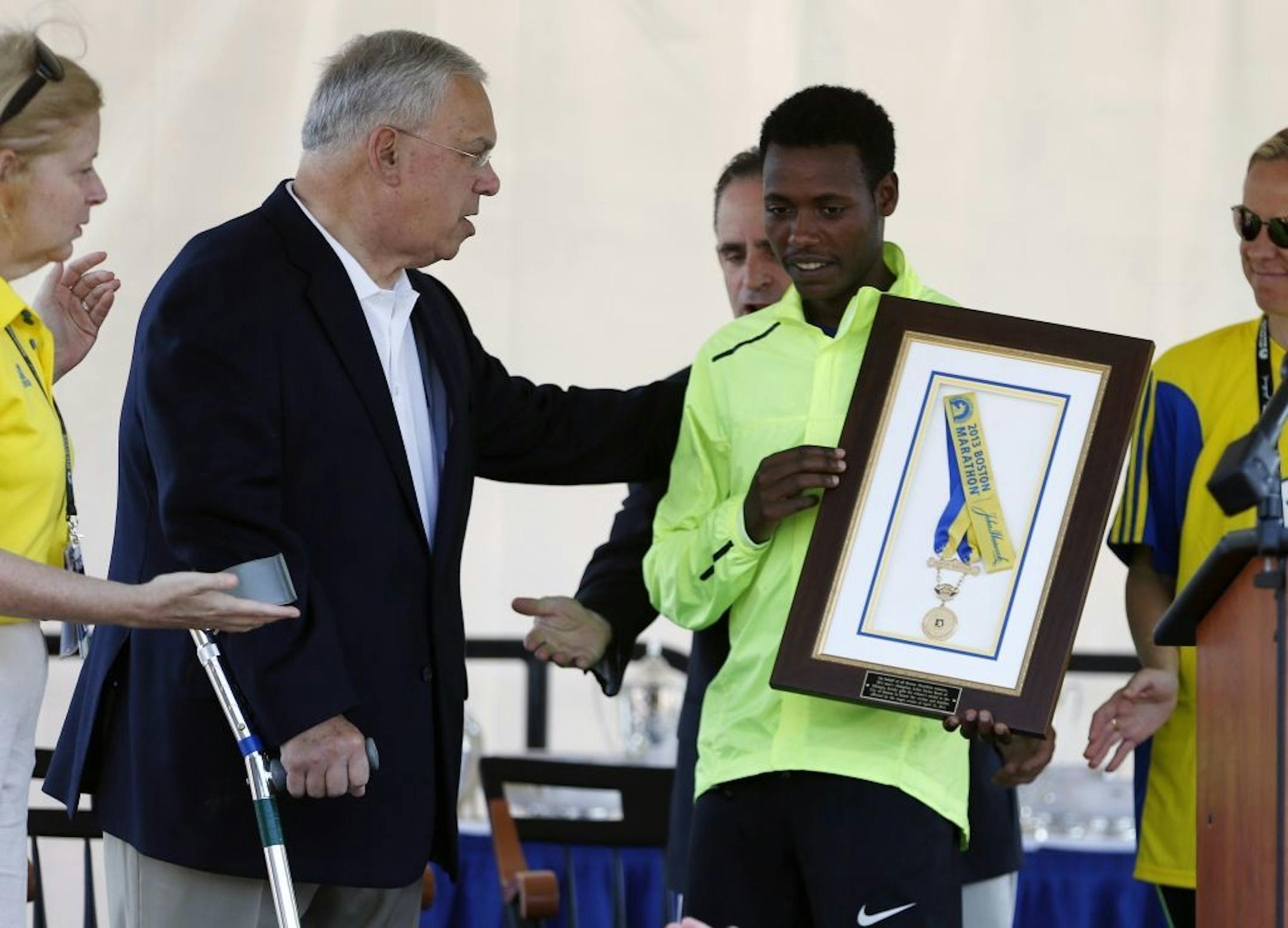 Boston Marathon 2013 men's winner Lelisa Desisa, center right, of Ethiopia, holds his medal with Boston Mayor Thomas Menino, center left, while presenting it to the city as a tribute to the victims of the Boston Marathon bombings, Sunday, June 23, 2013, in Boston.