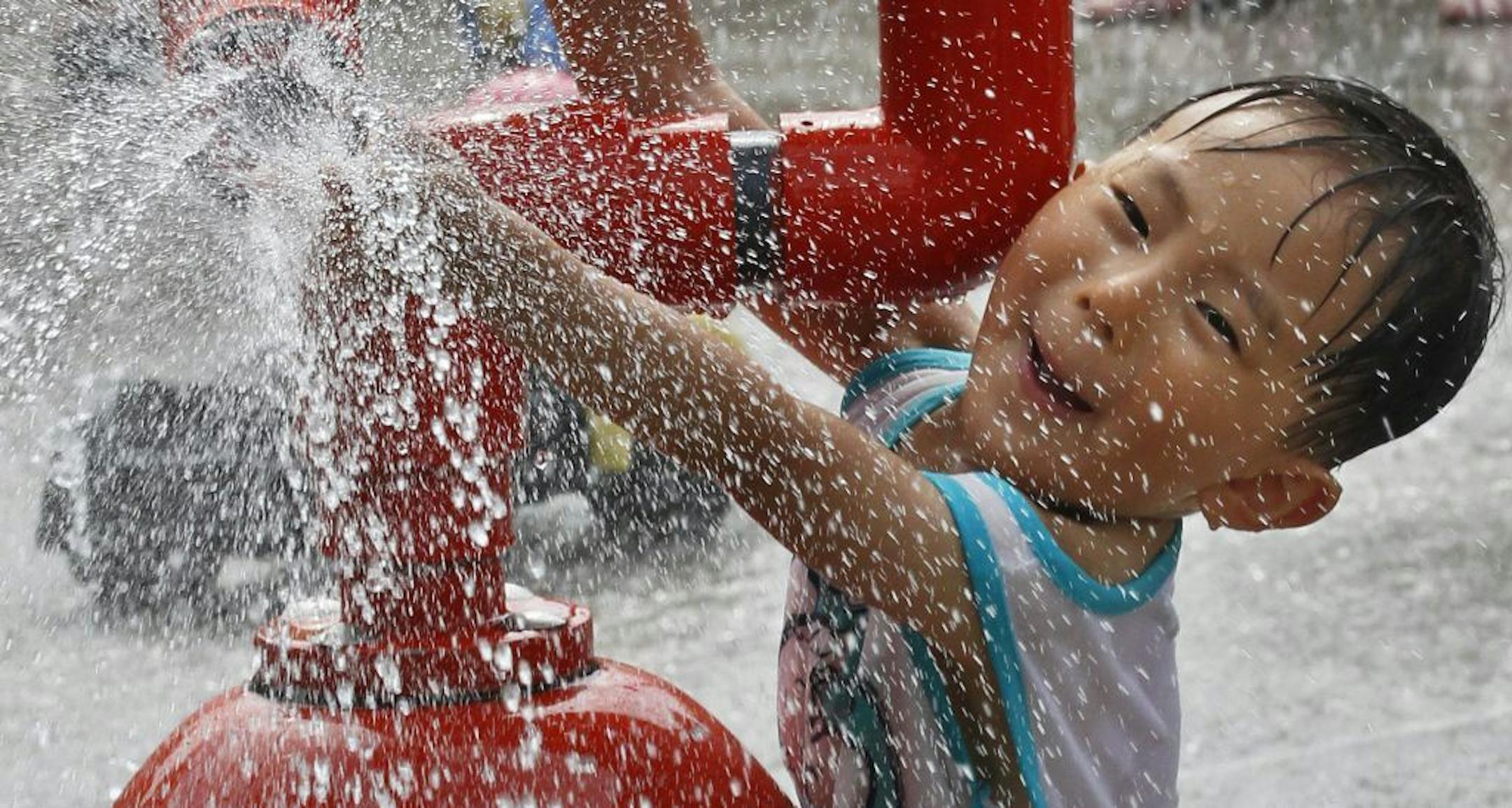 Hyuntae Yun of St. Paul cooled off in the Como Park Zoo wading pool as he commanded a water canon in the midst of numerous water sprays.