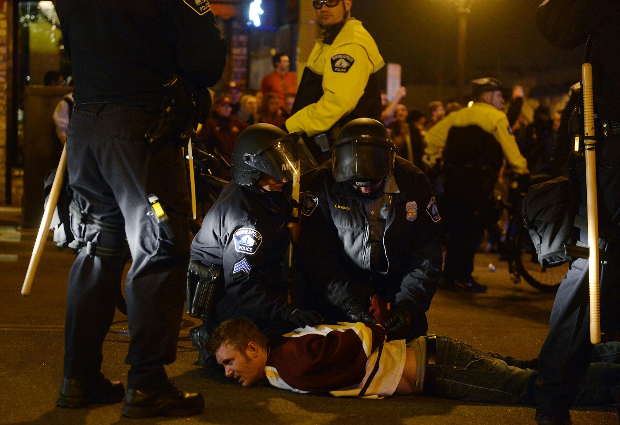 A man is zip-tied by Minneapolis law enforcement during a riot Saturday evening in Dinkytown, Minnesota. Minneapolis Police say 19 people have been arrested after crowds filled the streets of Dinkytown following the Gophers' NCAA hockey title game loss. (AP Photo/The Minnesota Daily, Chelsea Gortmaker) ORG XMIT: MIN2014041412564430