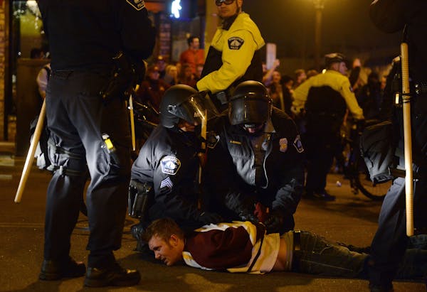 A man is zip-tied by Minneapolis law enforcement during a riot Saturday evening in Dinkytown, Minnesota. Minneapolis Police say 19 people have been ar