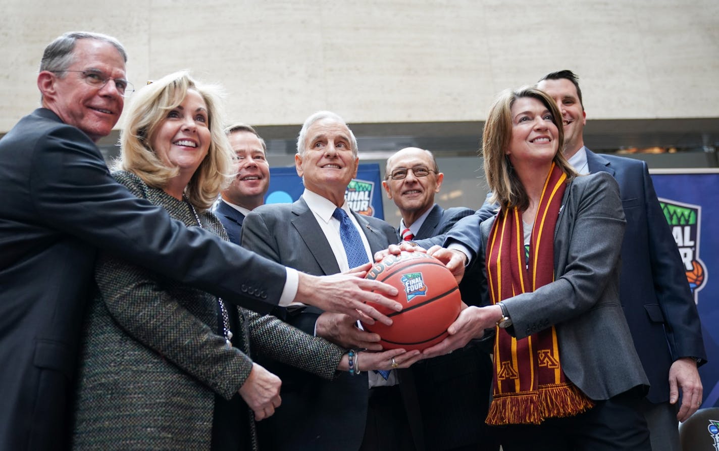 Richard Davis, Maureen Bausch, David Mortenson, Gov. Mark Dayton, Mike Vekich, Kate Mortenson, and Tom McGinnis got their hands on the ceremonial ball for the ceremonial handoff from Super Bowl Host Committee to the 2019 Final Four committee, marking the transition from football to basketball.