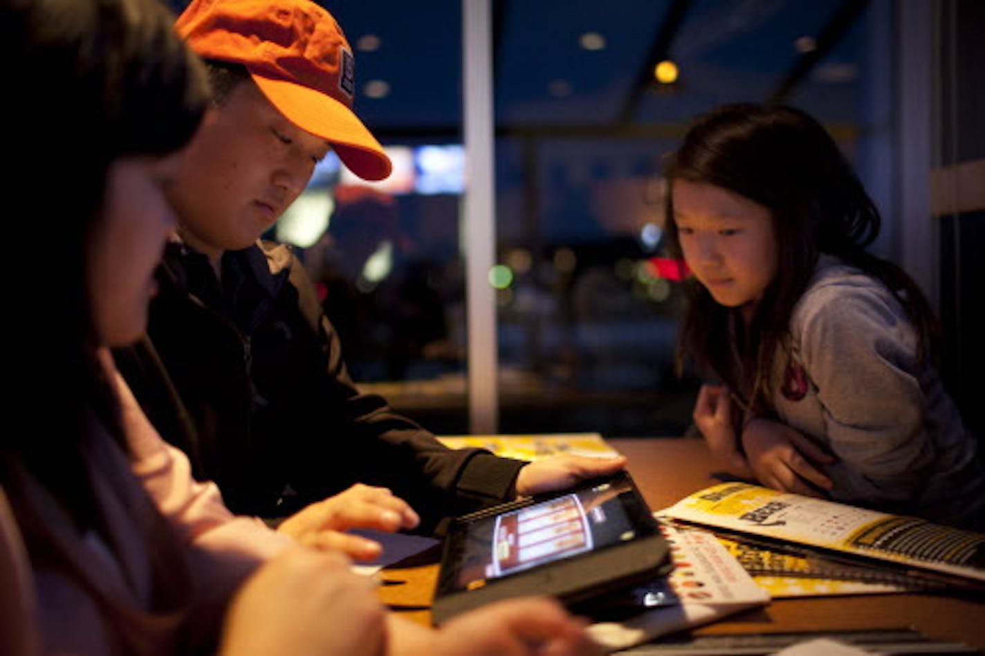 Buffalo Wild Wings is one of the first national restaurant chains to offer Apple iPads at tables so customers can order food, play games and pay their bills electronically if they wish. The concept is being test-marketed at their Oakdale, Minn. restaurant; if it goes well, a national roll-out will follow. Luke Amerson of St. Paul ordered wings with an iPad Tuesday night, March 6, 2012 at the Buffalo Wild Wings in Oakdale, Minn. At left was Sheng Hang. Hang's neice, Katrina, 10, was at right.] JE