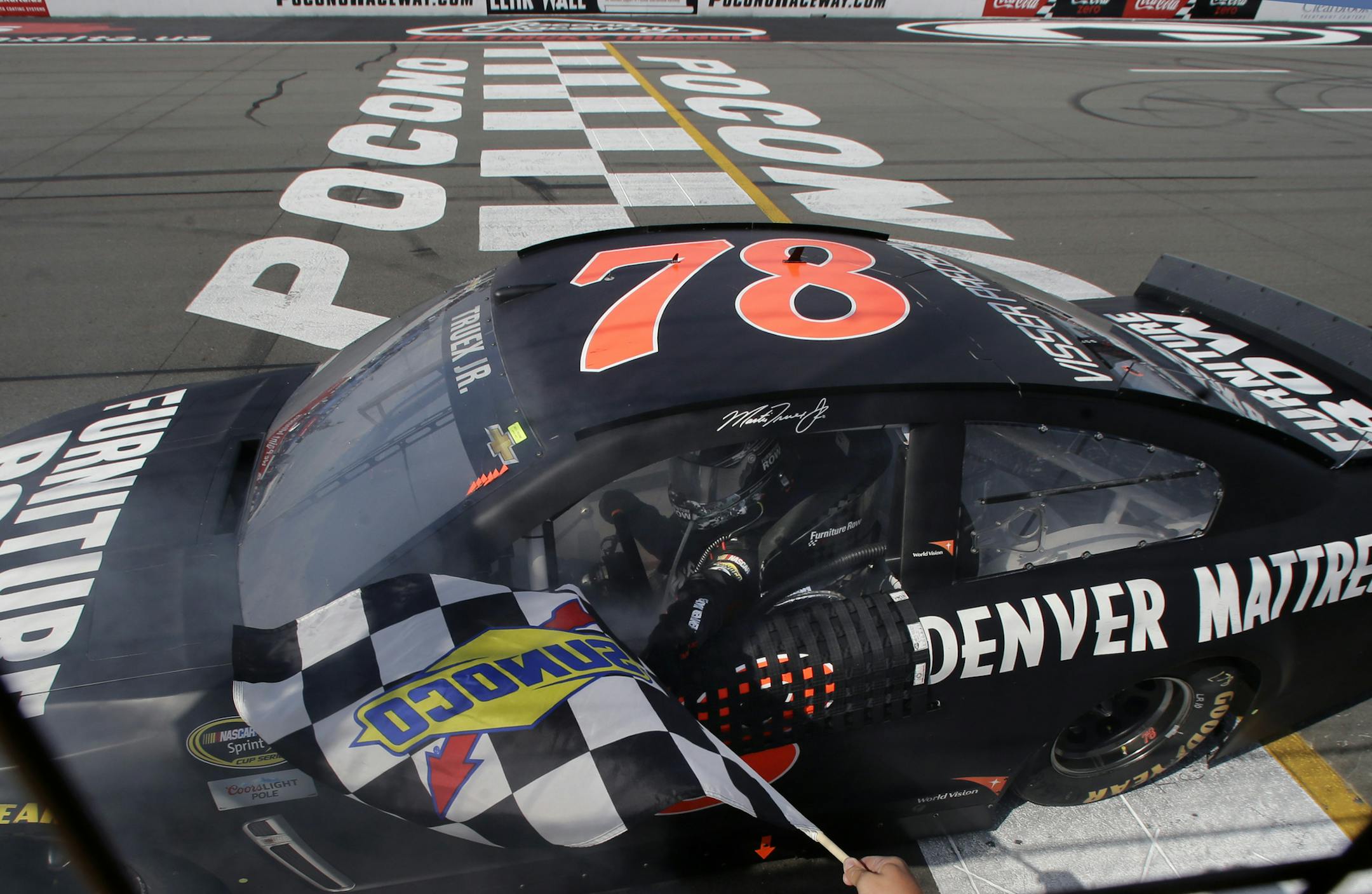 Martin Truex Jr. reaches for the checkered flag after winning a NASCAR Sprint Cup Series auto race at Pocono Raceway in Long Pond, Pa., Sunday, June 7, 2015. (AP Photo/Mel Evans)