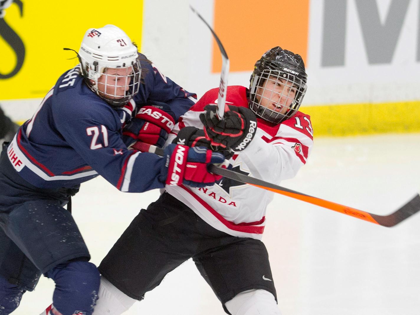 Canada's Caroline Quellette, right, takes a hit from USA's Hilary Knight during pre-Olympic women's hockey action in Calgary, Alberta, Thursday, Dec. 12, 2013.