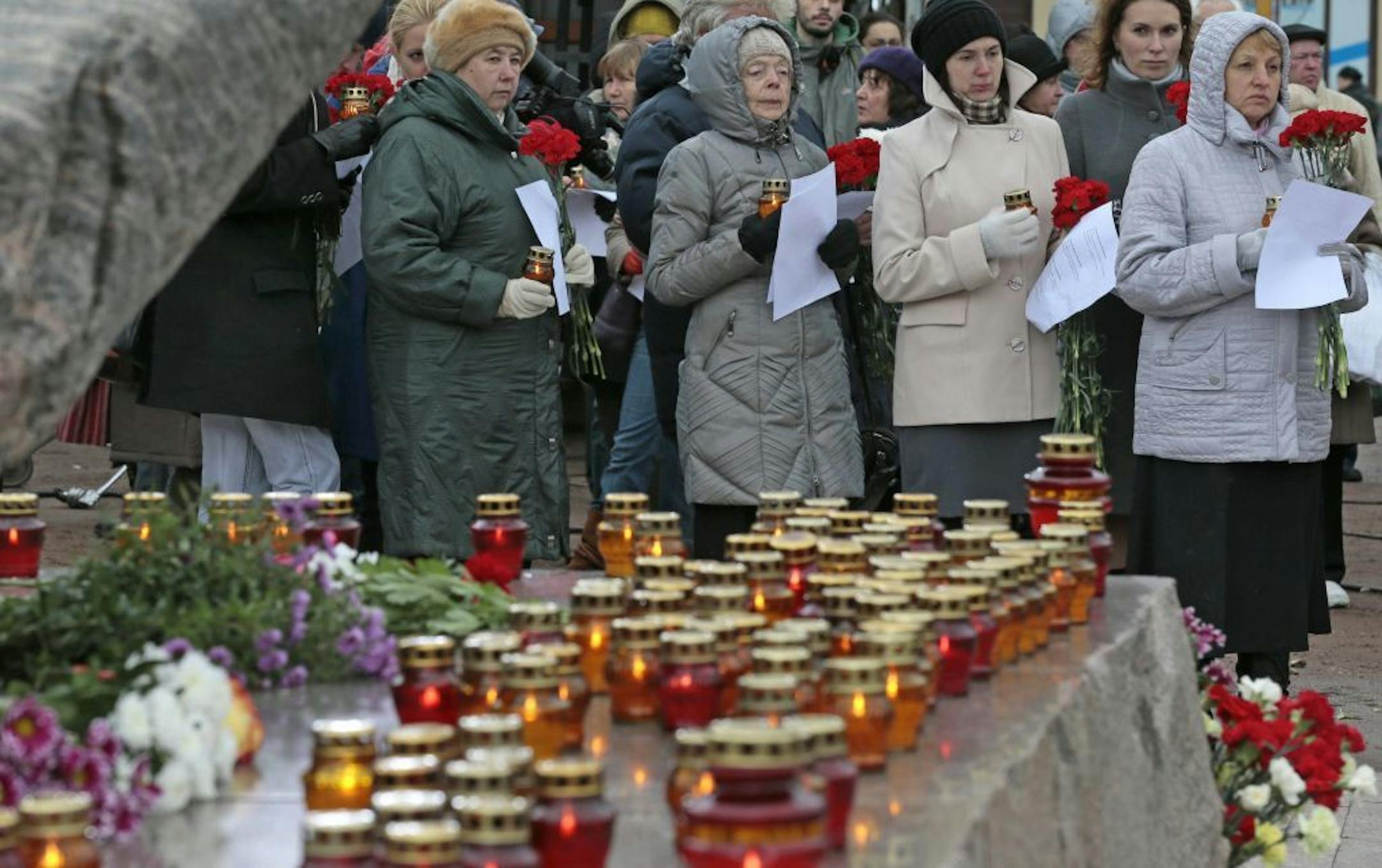 People line up to lay flowers at the Solovky Stone monument and to read out the names of victims of Soviet dictator Josef Stalin's purges in Lubyanka Square in Moscow, Russia, Monday, Oct. 29, 2012. On the eve of the Day of Victims of Political Repressions marked in Russia on Oct. 30, people gathered at the memorial, a giant slab of stone taken from a Soviet labor camp in the Solovky Islands, to commemorate thousands of victims of Soviet-era political repressions.
