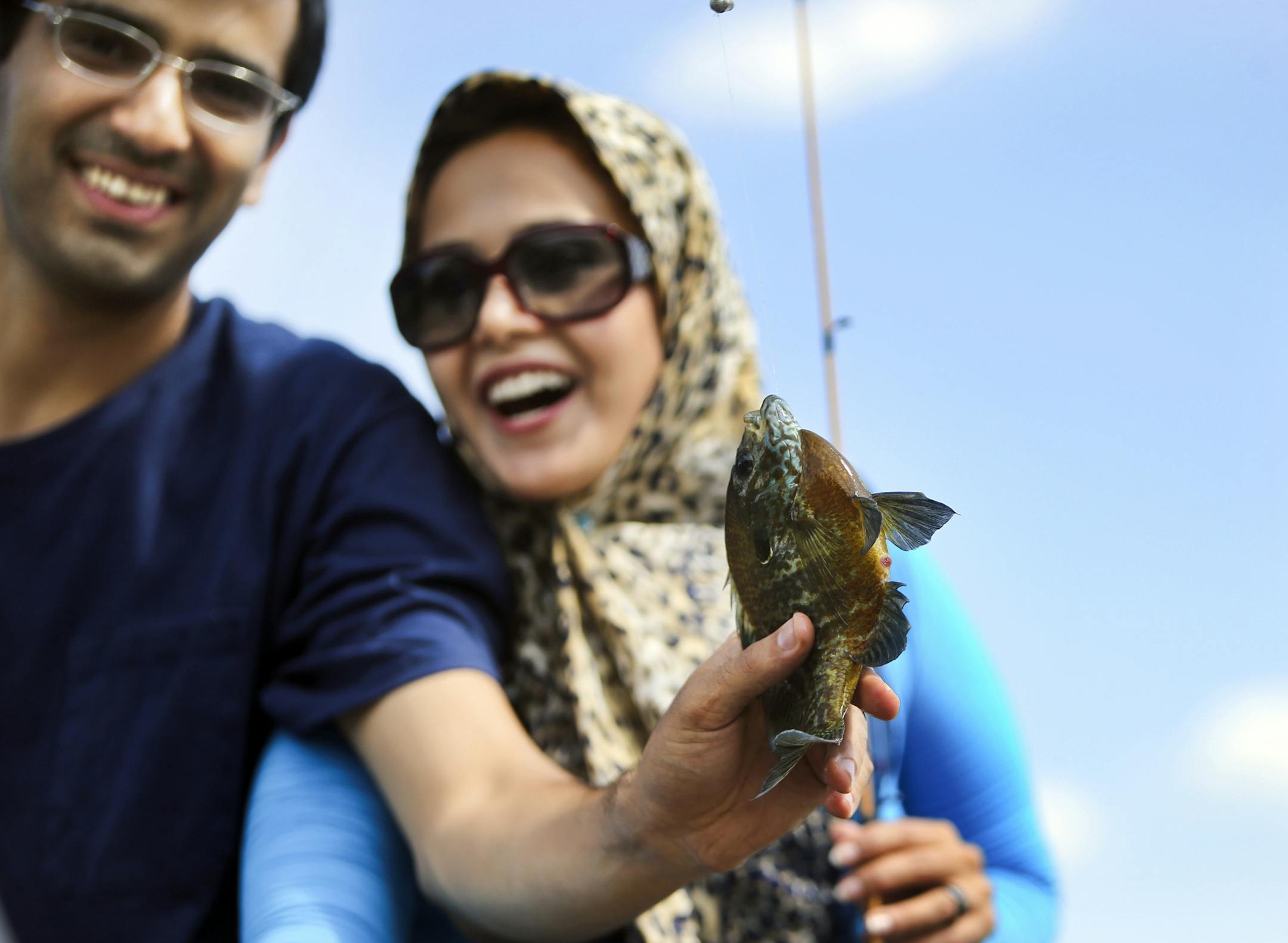 As part of the I Can!, husband and wife Alireza, left, and Zahra react to the pumpkinseed sunfish Alireza caught during the weekly Fishing Friday program Friday, June 6, 2014, at Fort Snelling State Park in St. Paul, MN. The pair are students at the University of Minnesota and it was their first time ever fishing.] (DAVIDJOLES/STARTRIBUNE) djoles@startribune.com I Can Fish! is among the DNR's I Can! programs designed for families to try for the first time, to give hands-on instruction from an ex