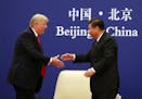 U.S. President Donald Trump, left, and Chinese President Xi Jinping prepare to shake hands during a business event at the Great Hall of the People in 