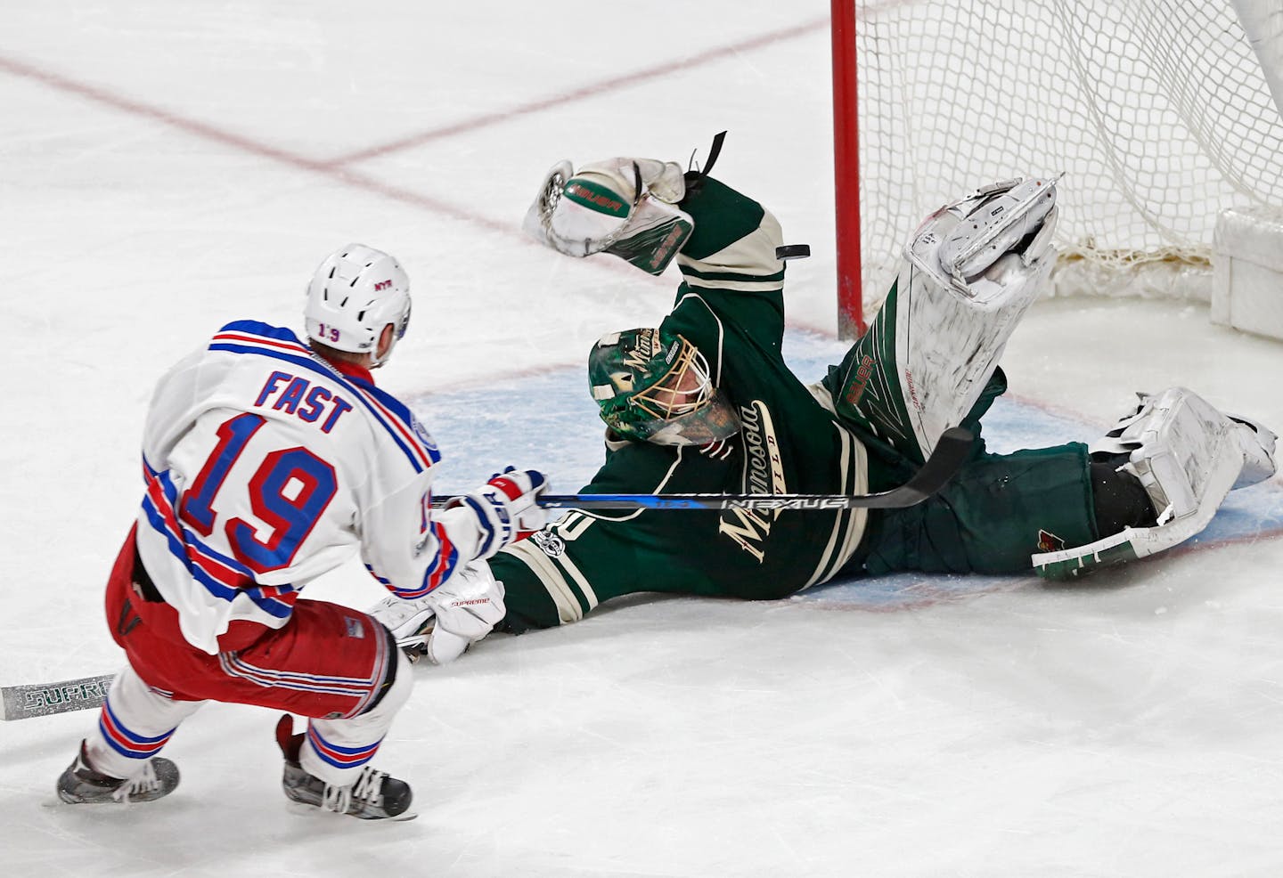 A falling Minnesota Wild goalie Devan Dubnyk, right, blocks a shot by New York Rangers' Jesper Fast during the first period of an NHL hockey game Saturday, March 18, 2017, in St. Paul, Minn. (AP Photo/Jim Mone)