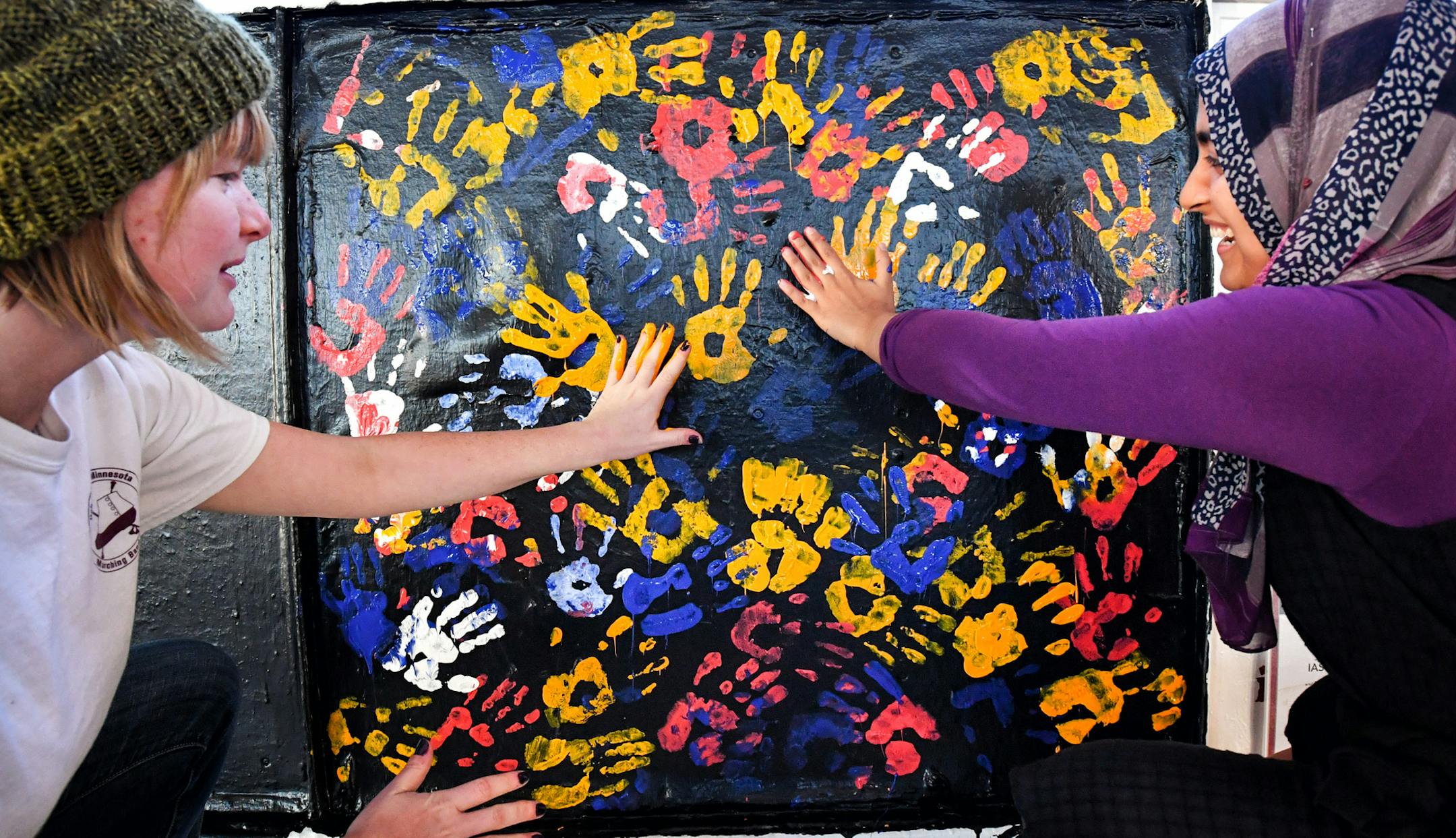 Libby Witte, left, and Sidhra Musani added their handprints to the mural. The Muslim Student Association invited students to help repaint the group’s defaced mural to show that “bigotry does not tear us apart, but rather brings us together.” Musani is president of the association.