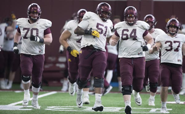 Offensive linemen Curtis Dunlap Jr. (51) and Conner Olson (64) ran on the practice field Tuesday at the University of Minnesota during spring practice