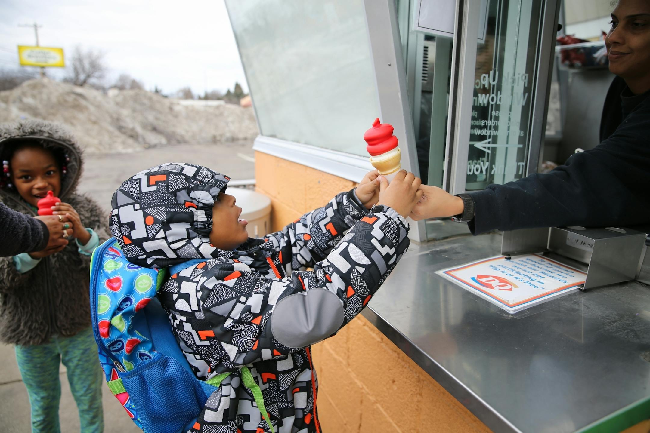 Five-year old Regime Buie-Williams grabbed a cherry dipped ice cream cone from the window after 6-year old Rayla Williams had started on hers Wednesday at a Dairy Queen in Roseville.