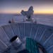 In this 2007 photo provided by Steffen Richter, the sun sets behind the BICEP2 telescope, foreground, and the South Pole Telescope in Antarctica. In t