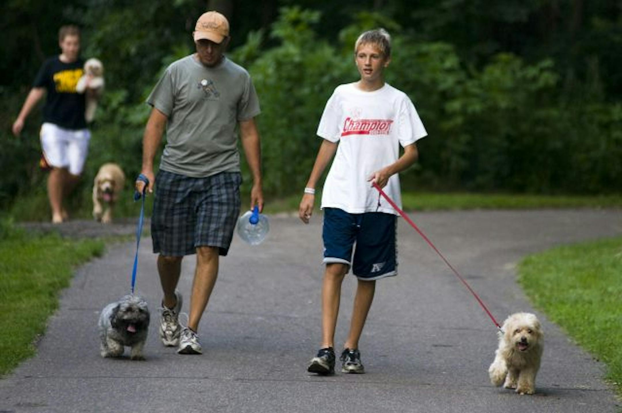 Scott Larson and his son Daniel of Lino Lakes walked their dogs Cooper and Rosie at Rice Creek Dog Park on Tuesday. Some dog owners say that adding a fence will attract dog owners who can't control their animals.