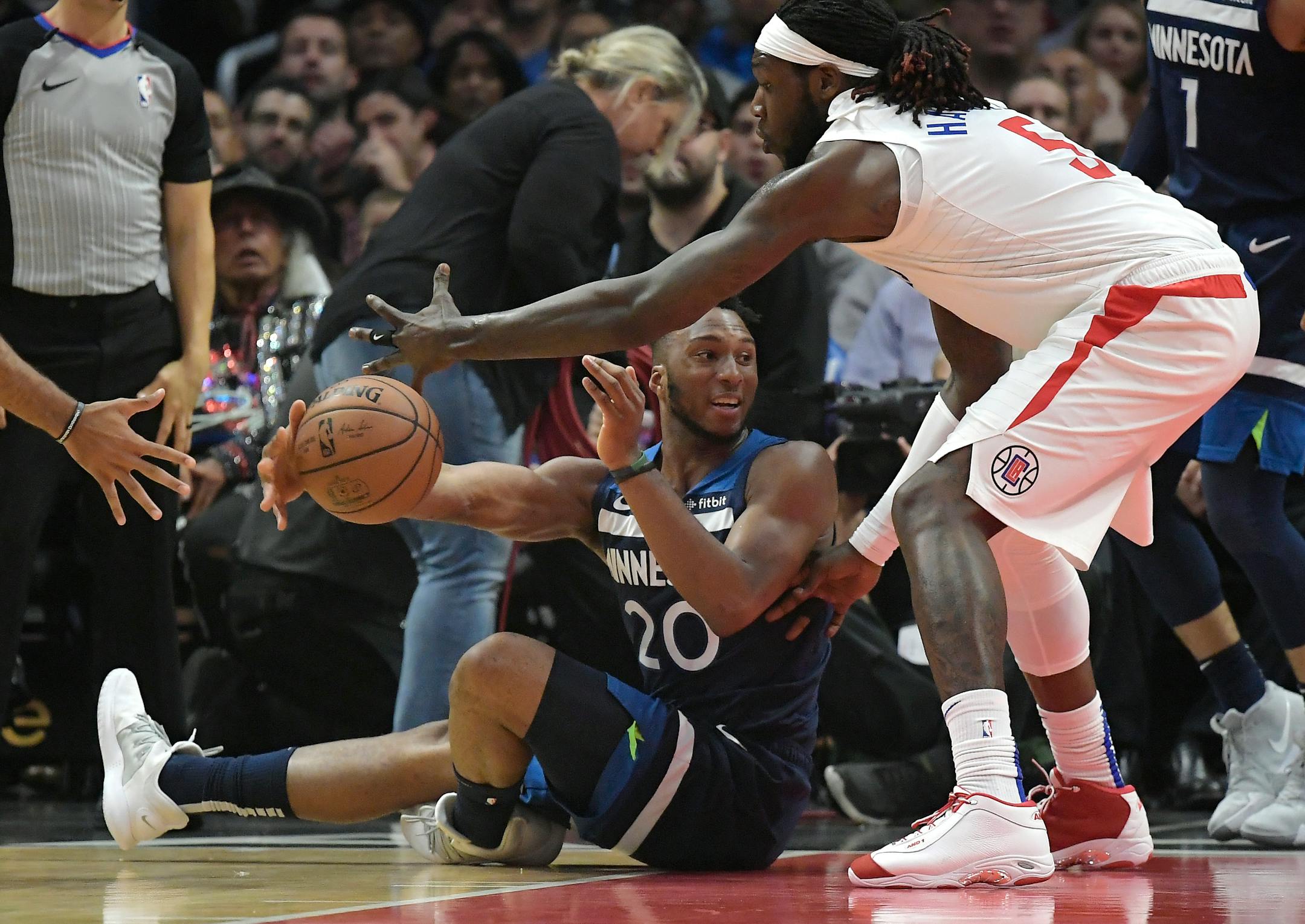 Timberwolves guard Josh Okogie tried to pass while seated on the floor and under pressure from Clippers forward Montrezl Harrell during the first half Monday.