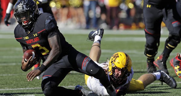 Maryland quarterback Tyrrell Pigrome, left, is tripped by Minnesota linebacker Carter Coughlin in the second half of an NCAA college football game in 