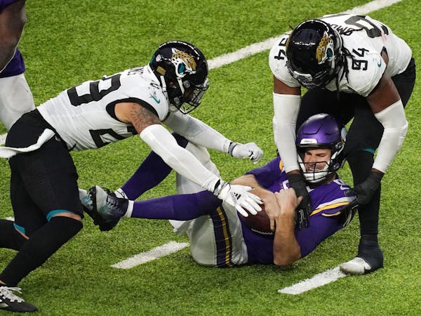 Kirk Cousins shielded the ball as he was dropped by defensive end Dawuane Smoot (94) in overtime on one of the Jaguars' season-high four sacks.