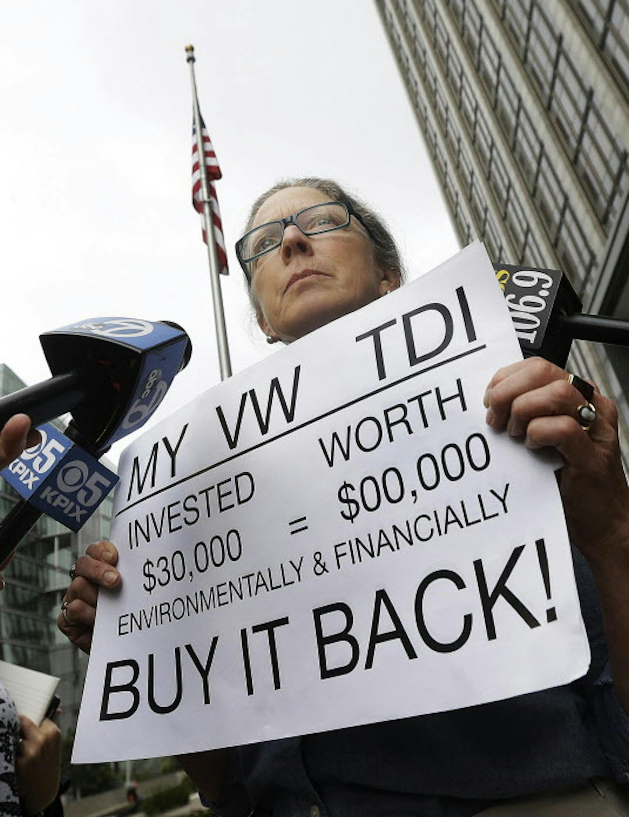 FILE - In this Thursday, April 21, 2016, file photo, Joyce Ertel Hulbert, owner of a 2015 Volkswagen Golf TDI, holds a sign while interviewed outside of the Phillip Burton Federal Building in San Francisco. Loyal owners of Volkswagen diesel cars understandably felt betrayed when they learned the German automaker had rigged the testing process to bypass U.S. emissions standards. Thanks to the settlement announced in June, people who bought or leased the affected vehicles are sorting through a com