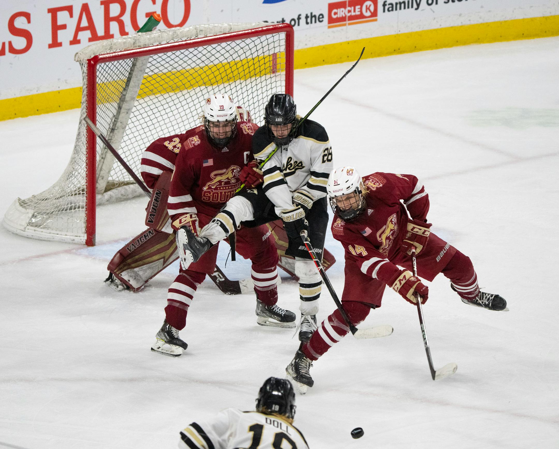Lakeville South Cougars forward Jackson Ernst (14) cleared the puck from in front of the Cougars' goal while Cougars defenseman John Novak (19) tangled with Andover Huskies forward Luke Babineau (28) in the third period.