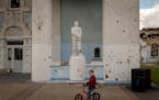 A young boy rides a bicycle past the entrance to Champions Stadium in Irpin, Ukraine, on Wednesday. The stadium sustained heavy damage during the figh