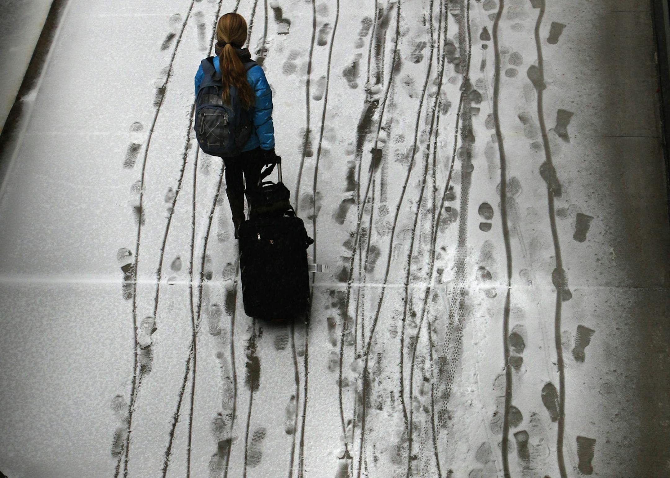 A sidewalk along 7th St. S. in downtown Minneapolis, quickly filled with ice and snow, making it somewhat treacherous for pedestrians to walk, especially those who were dragging luggage through the newly-fallen snow.