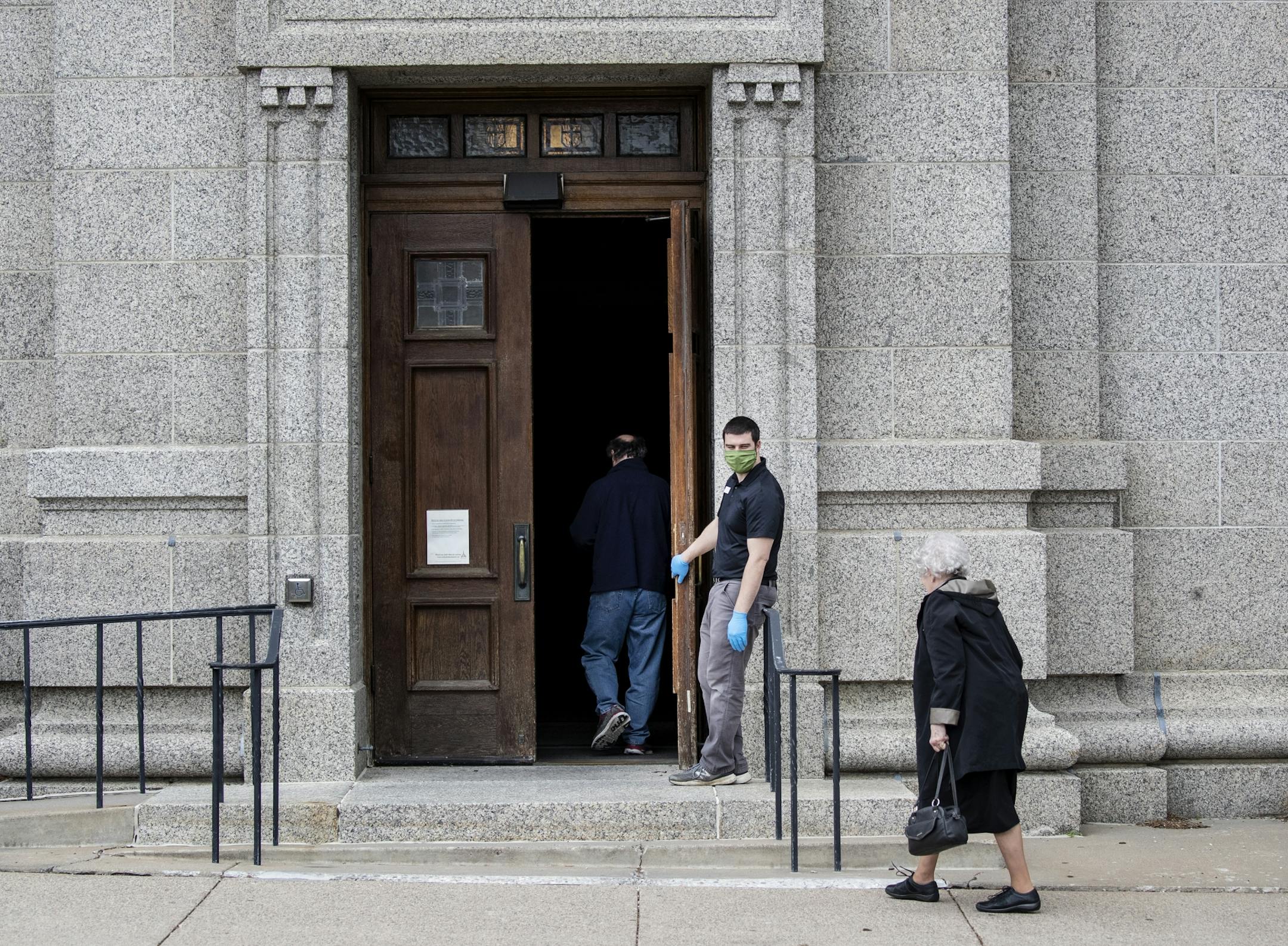 Ben Nelson held the door open for people heading into confession at the St. Paul Cathedral. Nelson works maintenance at the Cathedral. Part of his responsibility include sanitizing and making sure that there are under 10 people inside during confessions.