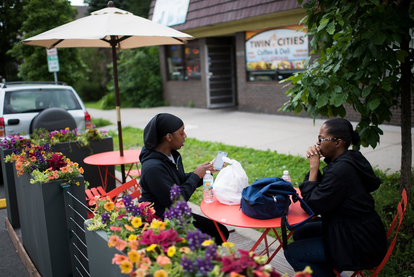 Shanay Ponder, left, brings up something on her phone while she sits with her mother, Inez Howard, at the new parklet seating outside of Twin Cities Coffee and Deli on Chicago Ave. on Wednesday. "This is the first time I've seen it," said Ponder of the new seating. "I love it." ] Isaac Hale � isaac.hale@startribune.com The city is expanding its Parklet program to include "street cafes", pop-up spaces to eat in curbside parking spots outside restaurants.