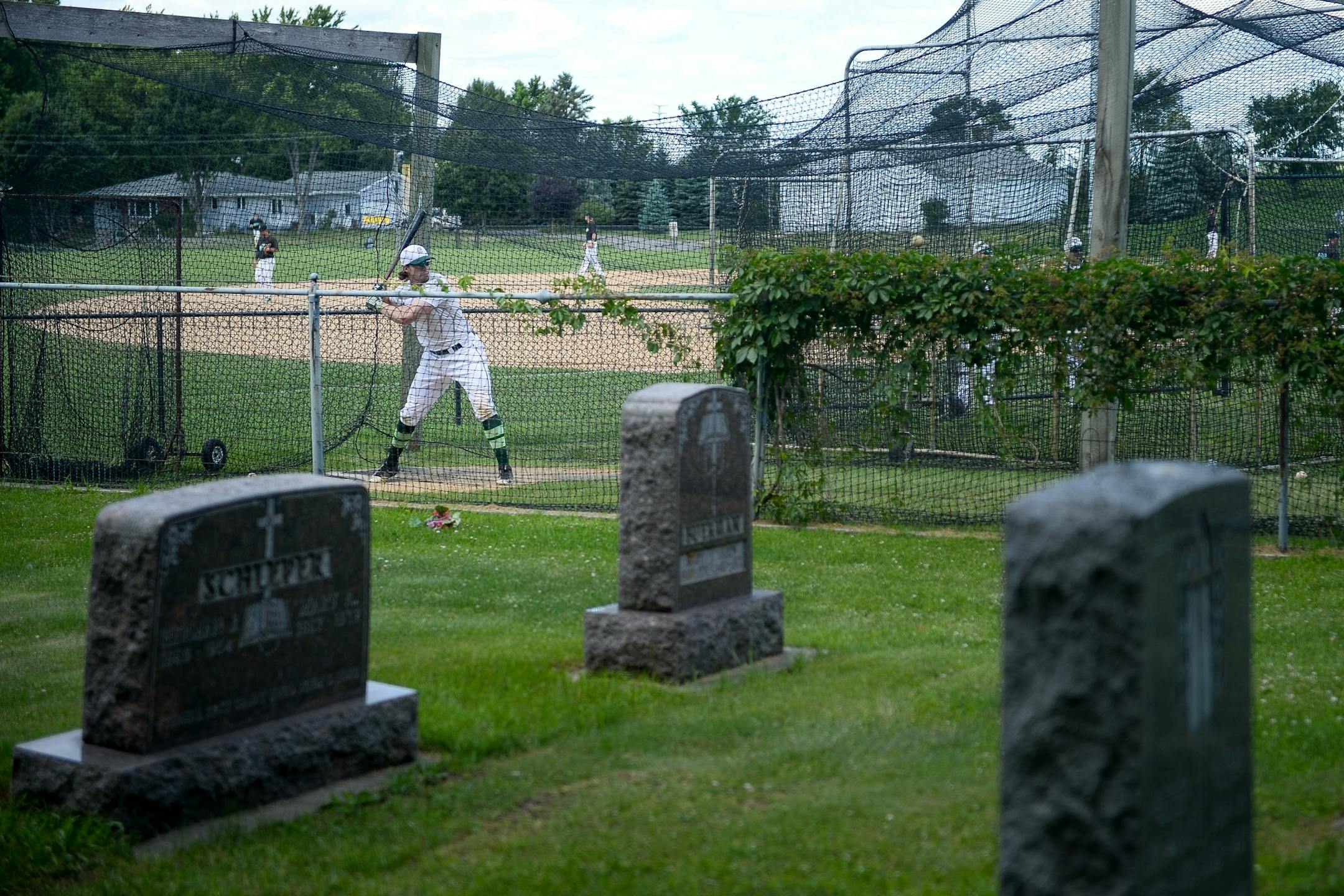 An Atwater player practiced batting in the cages at the Farming Flames Baseball field on Sunday, June 25, 2017 in Farming, Minn. The field butts up against the town's cemetery.