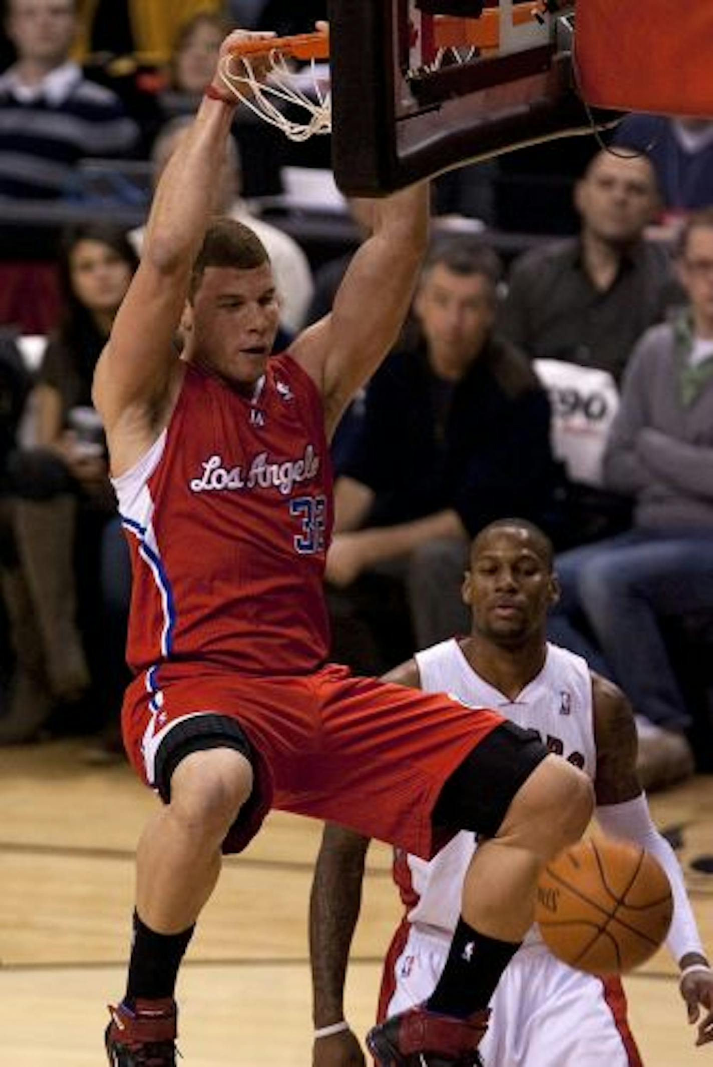 Los Angeles Clippers' Blake Griffin, right, hangs from the basket after scoring on Toronto Raptors' Sonny Weems during the first half of an NBA basketball game, Sunday, Feb. 13, 2011, in Toronto.