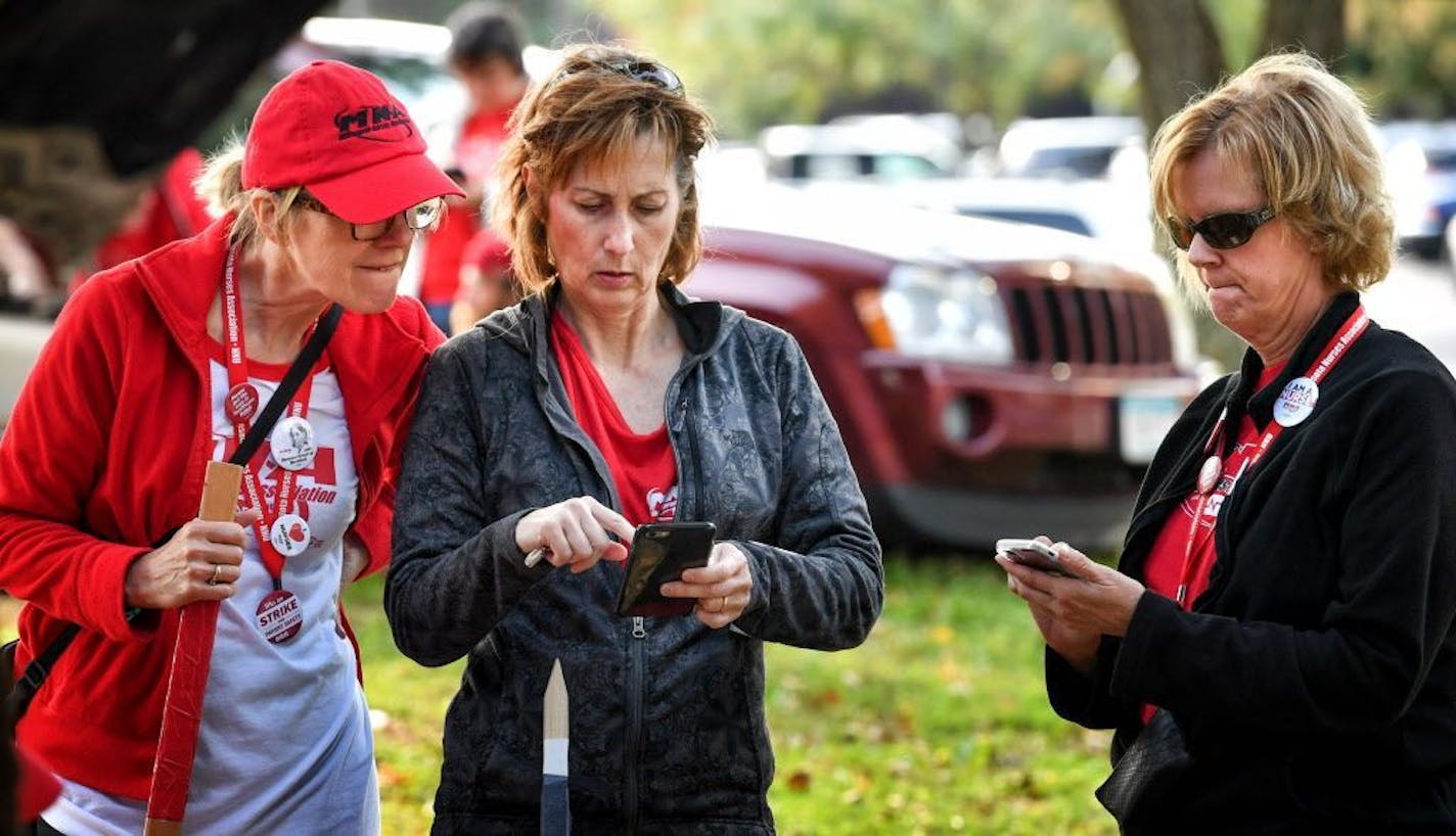 Allina nurses Mary Dunn Mann, Lisa Green and Shari Eaton check their phones to see how others were reacting to the tentative agreement Tuesday. They couldn't find anyone who was for it and vowed to vote "no"as they stood outside Abbott Northwestern Hospital in Minneapolis.