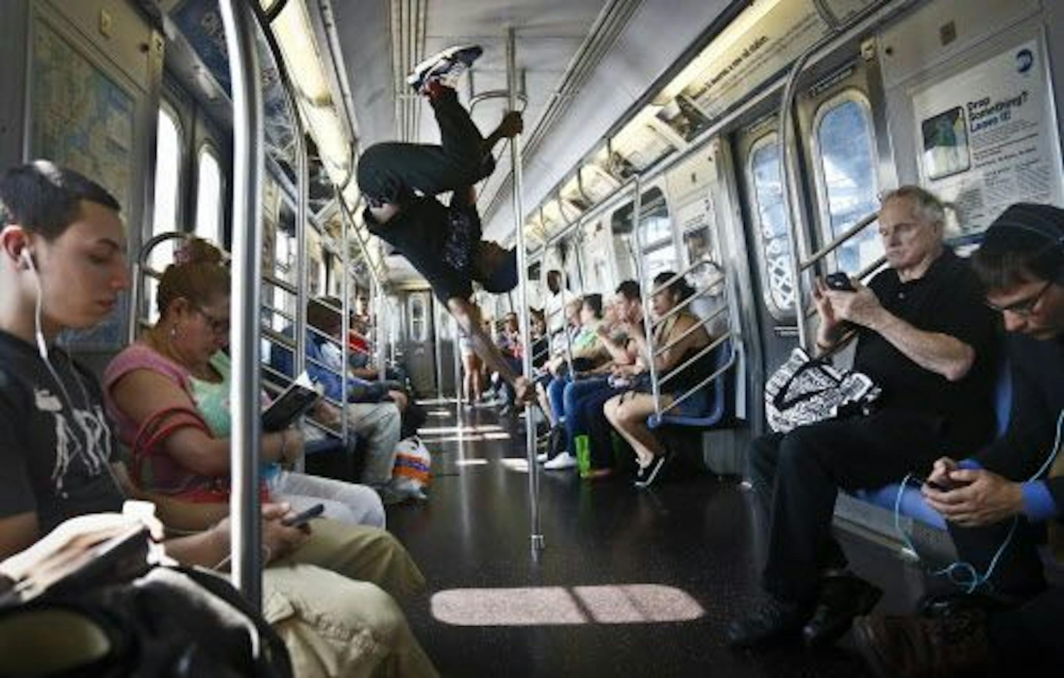 In this June 17, 2014 photo, Dashawn Martin, center, a member with the dance troupe W.A.F.F.L.E., which stands for We Are Family For Life Entertainment, performs on a subway, in New York.