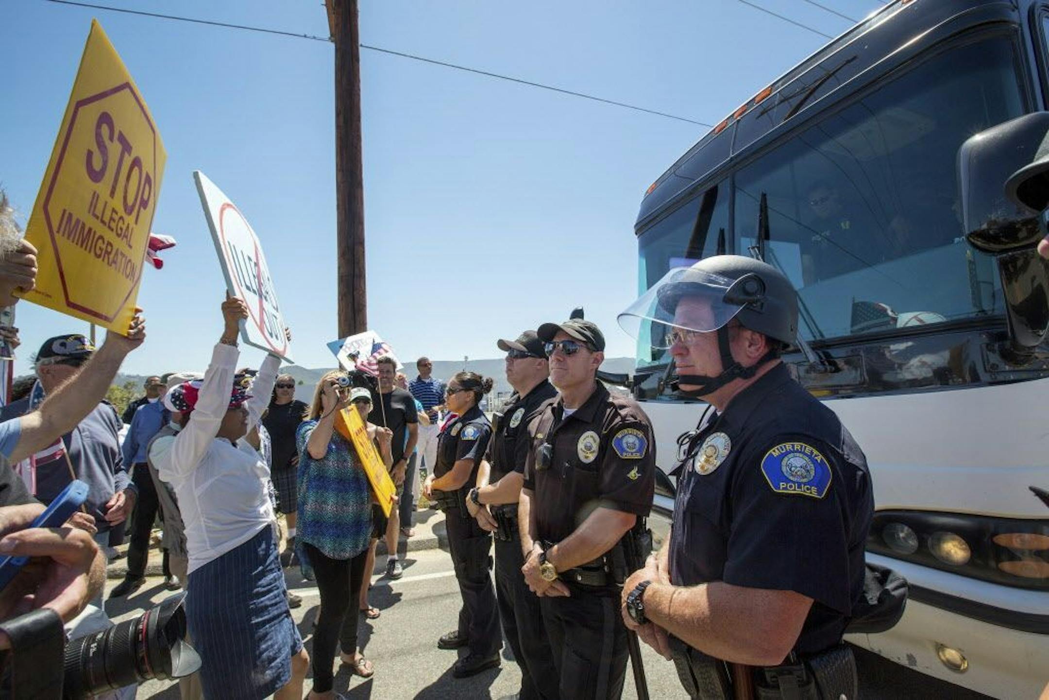 FILE -- Anti-immigration protesters gather in front of a Border Patrol station in Murrieta, Calif., to block a bus of migrants transferred from overcrowded facilities in Texas, July 1, 2014.