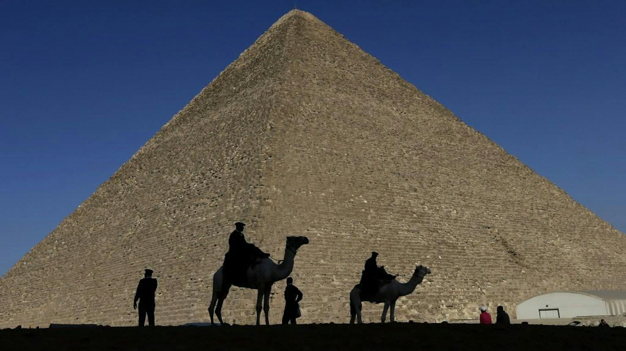 FILE - In this Dec. 12, 2012 file photo, policemen are silhouetted against the Great Pyramid in Giza, Egypt. Scientists have found a previously undiscovered hidden chamber in Egypt's Great Pyramid of Giza, the first such discovery in the structure since the 19th century. In a report published in the journal Nature on Thursday, Nov. 2, 2017, an international team says the 30-meter (yard) void deep within the pyramid is situated above the Grand Gallery, and has a similar cross-section.