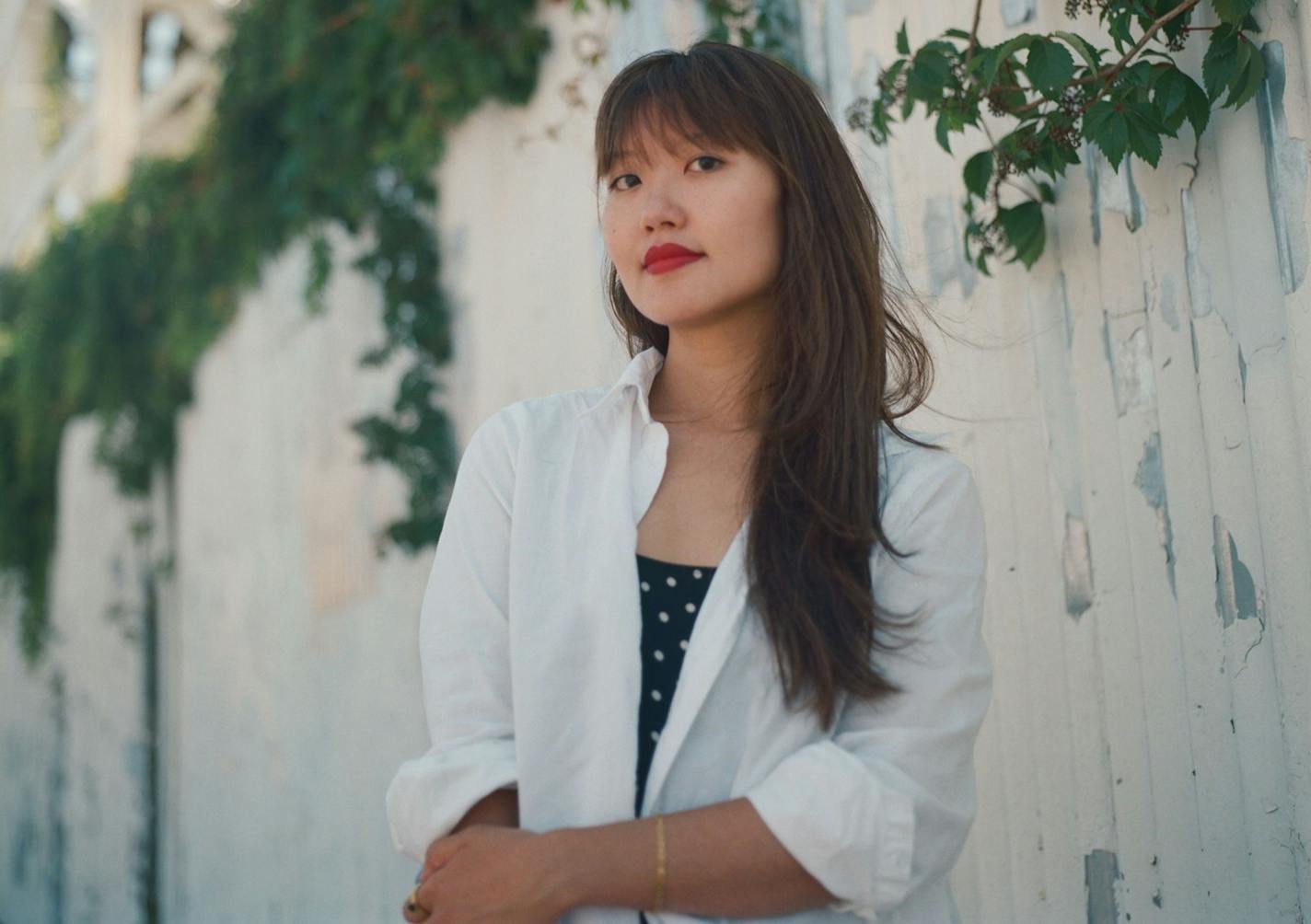 photo of author Katie Yee in front of a white, vine-covered wall