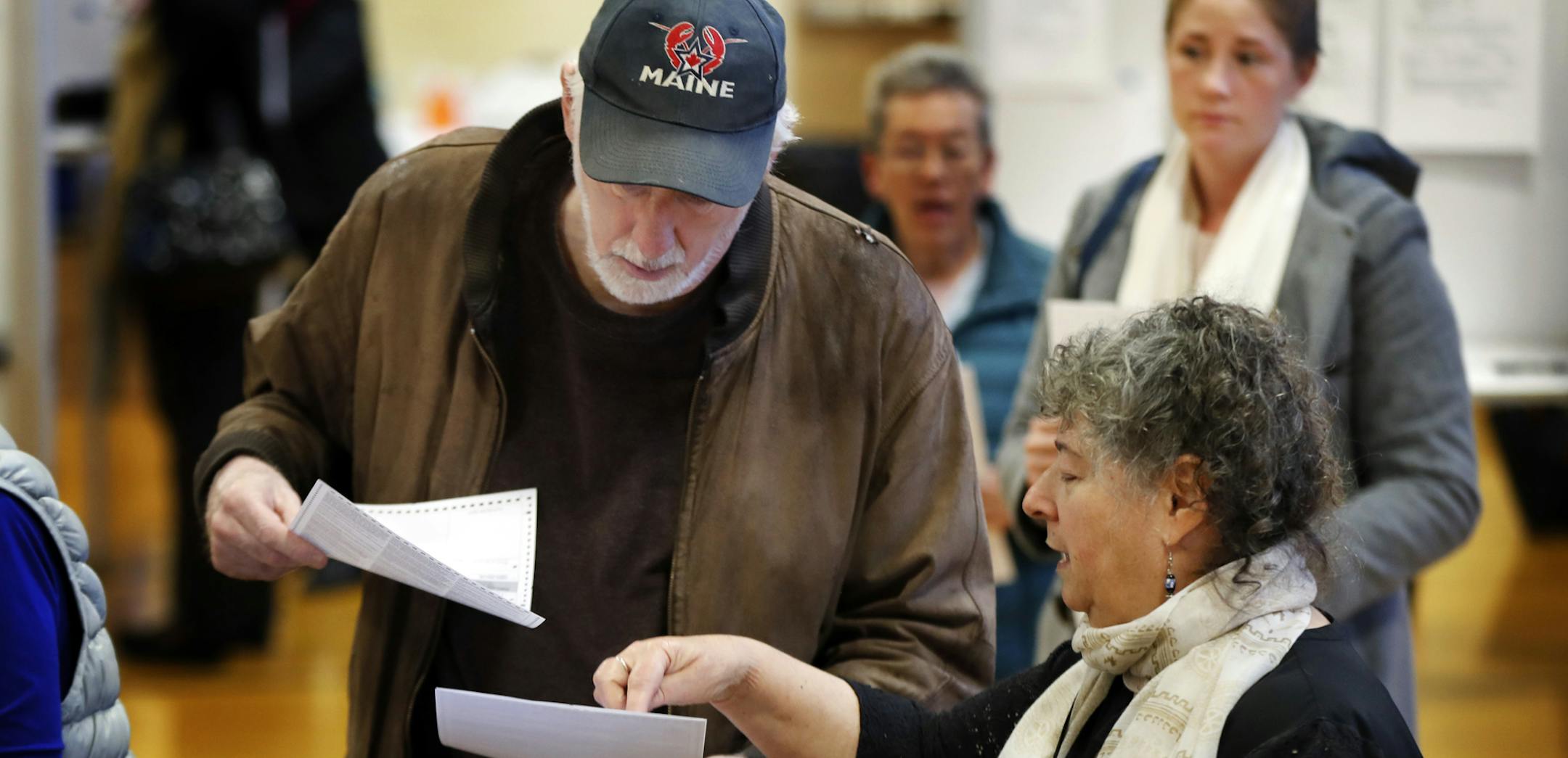 Michael Parent, left, gets instructions on submitting his ballots from warden Denise Shames while voting Tuesday, Nov. 7, 2017, in Portland, Maine. Voters in Maine will decide if they want to join 31 other states and expand Medicaid under former President Barack Obama's Affordable Care Act. It's the first time since the law took effect that the expansion question has been put before voters. (AP Photo/Robert F. Bukaty)