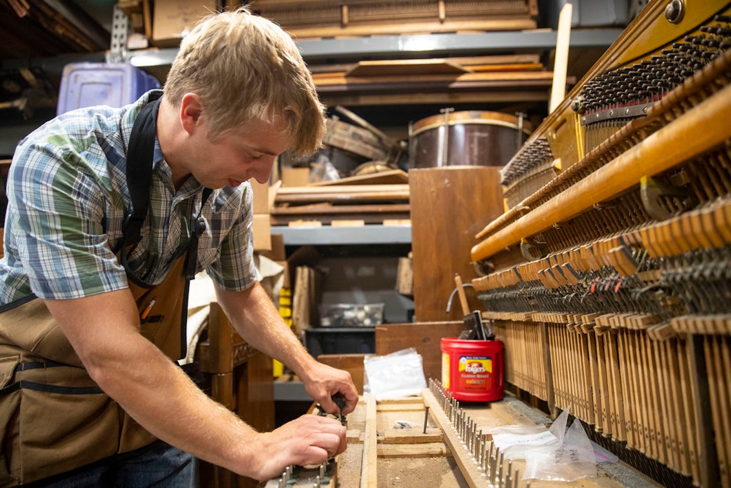 Nate Otto repairs player pianos in the workshop of his Anoka home. He cleaned front rail pins on a piano he is fixing up to replace his own.