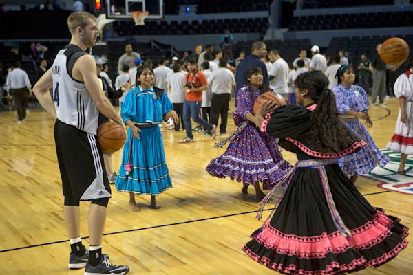 Robbie Hummel of the Minnesota Timberwolves holds a ball as women from to the Tarahumara Indigenous basketball team, from Mexico's Chihuahua state, pr